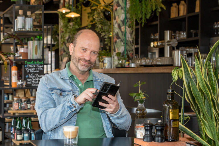 Man in cafe met BeterDichtbij app